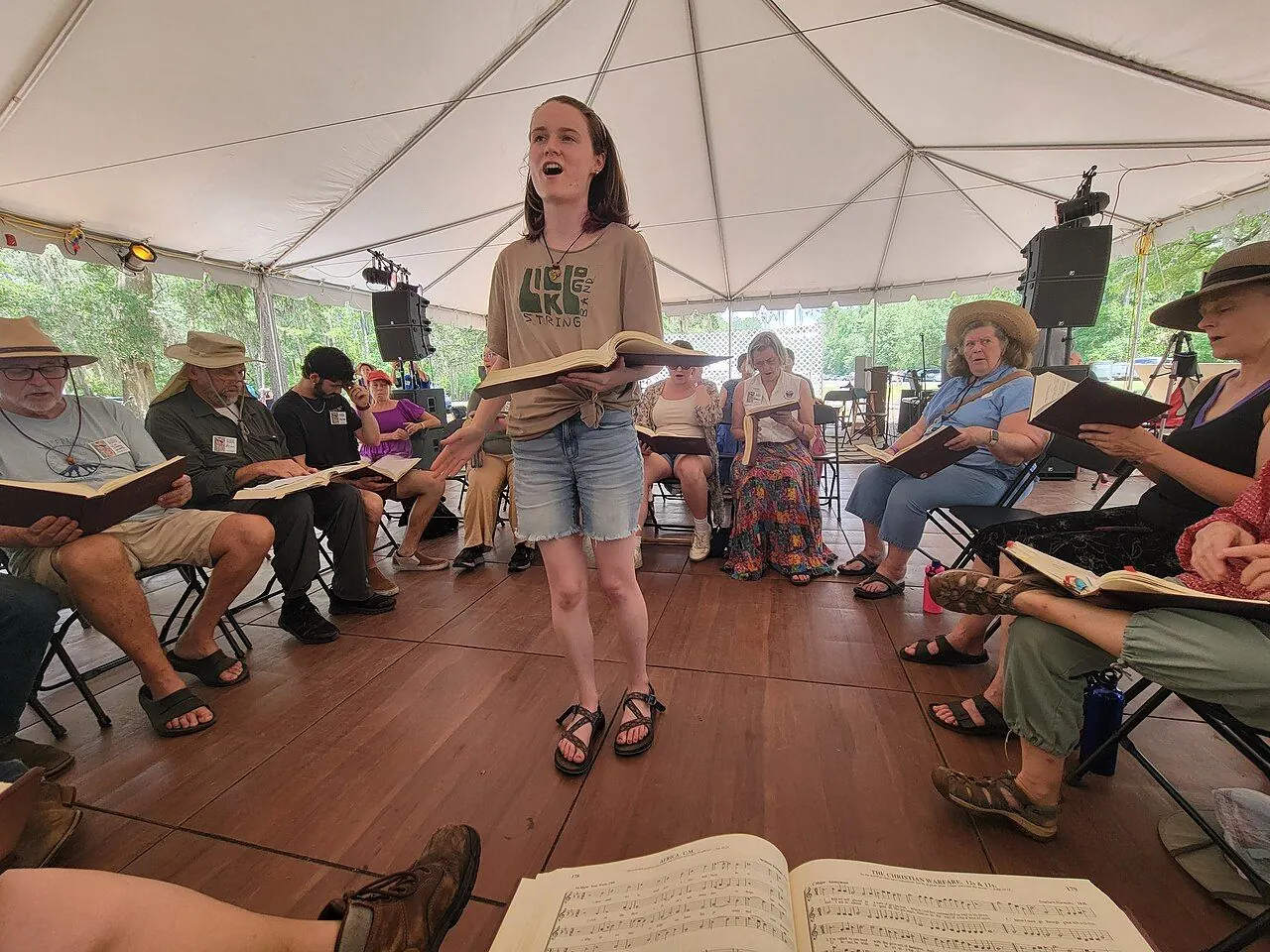 Singers seated in a hollow square with tunebooks